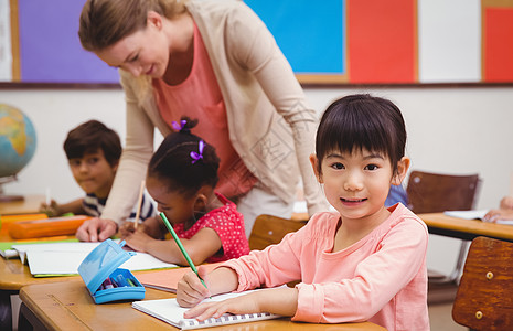 在课堂上对着镜头微笑的可爱学生椅子学校童年知识女孩学习班级桌子男生教学图片