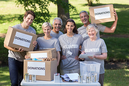 快乐的志愿家庭拿着捐赠箱环境桌子服务团队晴天组织衣服机构捐款盒子图片