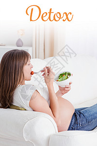 对躺在沙发上吃沙拉的 美丽的孕妇进行戒毒治疗图片