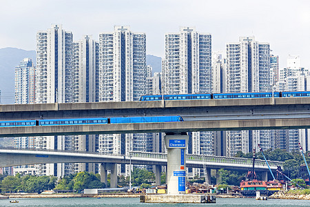 香港市市区桥上高速火车 车速超快运输财产绿色城市土地天空单轨蓝色高楼住宅图片