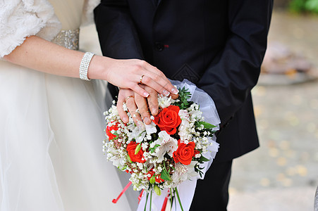 新娘和新郎的手 用戒指在花束上图片