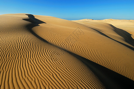 橙色柔软的沙漠沙子海浪天空太阳勘探旅行沙丘风雨蓝色荒野阴影图片