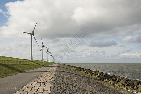 荷兰堤坝附近的现代风力车现代风力车涡轮灯芯自行车能源电力堤防生产人行道涡轮机砖块背景图片