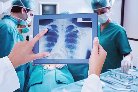 医生在平板电脑上看X光的复合图像手术帽成人制服服务专家男性男人操作设备手术室图片