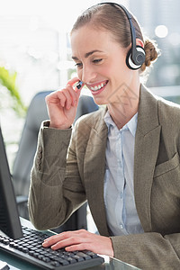 使用计算机戴头盔的微笑女商务人士办公室耳机职场代理人呼叫女性商务浅色技术金发图片