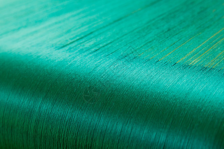 一家纺织厂织物机的折叠圈上的绿丝绸织物牙线翘曲细绳工厂纺织布料纺织品纤维编织图片