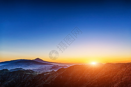 太阳在蓝天的山上照耀日落阳光阴霾火山天空蓝色图片