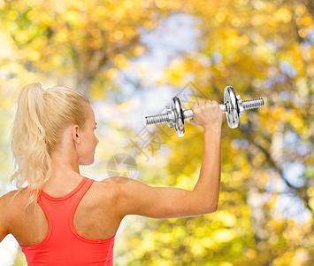 后面有重钢铁哑铃的女运动员数字锻炼健身房身体重量力量二头肌肌肉手臂运动图片