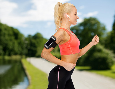 运动妇女用智能手机和耳机奔跑跑步微笑训练收音机公园技术玩家播客慢跑者减肥图片