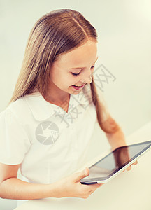 学校里带着平板电脑微笑的女孩课堂学习瞳孔知识互联网家庭作业桌子玩家学生童年图片