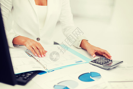 手持计算器和纸张的妇女审核后勤图表税收计算器工作工人数据薪水商务图片