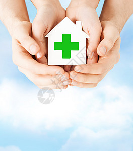 手持绿色十字的纸屋帮助机构组织药店服务父母庇护所志愿者贫困手掌图片