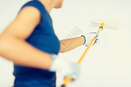 妇女用滚滚和油漆涂墙彩色女孩工匠工艺画家绘画装潢家务白色公寓空白背景图片
