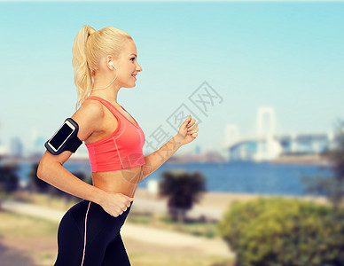 运动妇女用智能手机和耳机奔跑手臂跑步城市女孩重量歌曲技术臂章收音机音乐图片