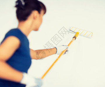 妇女用滚滚和油漆涂墙彩色空白画家装修工艺公寓乐器女孩墙壁白色工具背景图片