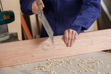 木匠剪切一块小块工作桌子手锯财产职业手工具木板木头男性木工图片
