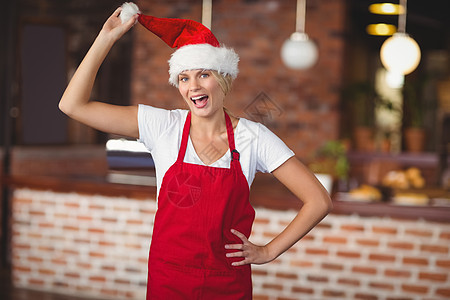 漂亮的女服务员摸她的圣诞帽子女性咖啡店雇主商业餐厅饮料在职金发女郎咖啡围裙图片