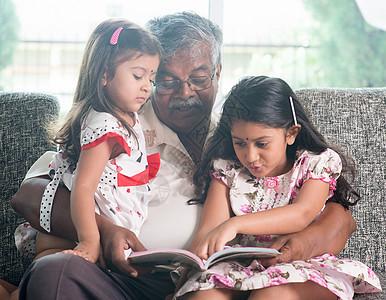 家庭阅读书合在一起女孩们爷爷沙发女儿们孙女教育男性微笑故事祖父图片
