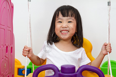 亚裔中国小女孩玩摇摆游戏微笑操场孩子青年喜悦女孩公园快乐幸福闲暇图片