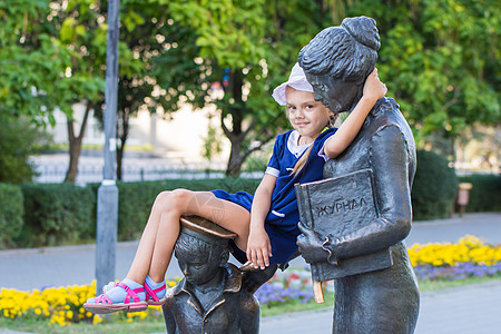 那女孩坐在第一个老师的纪念碑上 舒服地坐着图片