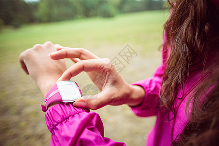 女人在徒步旅行时 用她的智慧手表智能锻炼女性勘探闲暇风景冒险家绿色设备手腕图片