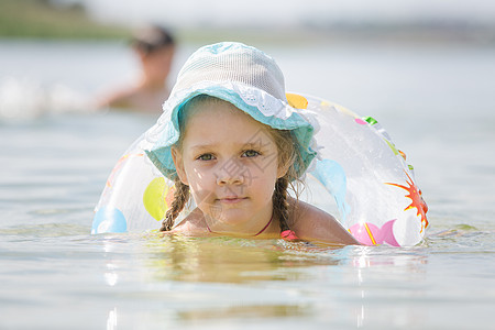河里游泳孩子集中四岁女孩的注意力 在河里漂浮着圆圈背景