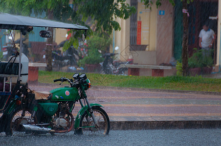 Tuktuk 在贡布的雨季风中进行自动循环运输出租车天气下雨街道摩托车摩托人力车背景图片