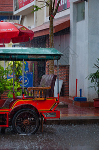 Tuktuk 在贡布的雨季风中进行自动循环人力车街道运输天气摩托摩托车出租车下雨背景图片