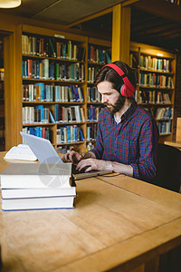 在图书馆学习的一流学生知识分子音乐专注校园电脑男性知识学校书柜大学生图片