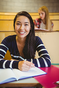 在笔记本上写作的微笑学生女性青少年报告高等教育女孩知识修订班级学校笔记图片