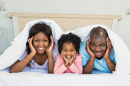 幸福的一家人躺在床上童年微笑棉被卷发住所家庭母亲女儿男性房子图片