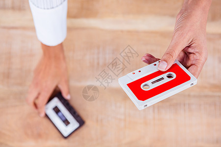 持有旧磁带的妇女木桌音乐记录木头桌子白色空白塑料红色立体声背景图片