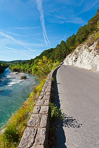 沿河公路沥青天空鹅卵石顶峰蓝色石灰石环境树木峡谷溪流图片