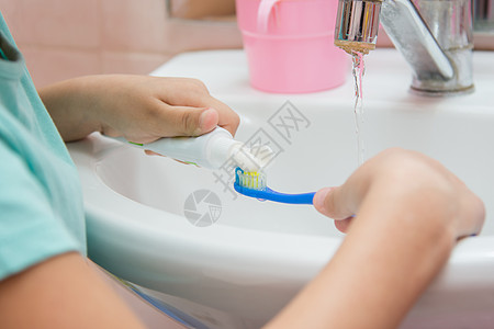 孩子从牙刷上的管子上挤压牙膏图片