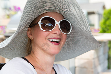 相机配件穿着帽子和太阳眼镜的妇女在户外笑背景