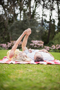 幸福的情侣抱在毯子上软垫浅色快乐男人草地小憩拥抱说谎公园篮子图片