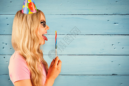 长着巨棒棒棒棒糖的 美丽时装怪人侧景的复合图像女士小吃帽子木板蓝色长发生日地板金发女郎气球图片