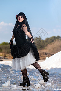 穿哥特服装的少女风俗姿势裙子面纱黑色女孩衣服靴子池塘女士背景图片