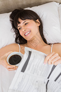 女人躺在床上 喝着咖啡图片