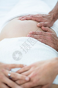 从按摩师那里接受胃部按摩的孕妇说谎肚子身体治疗孕妇装生活方式卫生奢华毛巾水疗背景图片