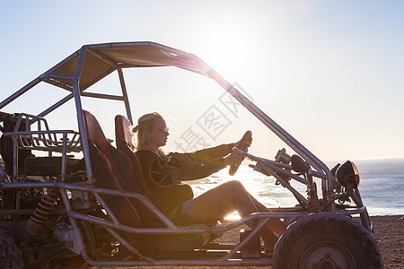 女人在日落时驾驶四重车沙滩车辆车轮乐趣自行车引擎海滩行动女孩冒险图片