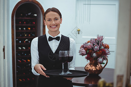 带着红酒杯托盘的微笑女服务员桌子女性瓶子衬衫马甲商务酒窖人士快乐服务图片