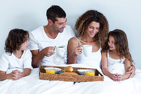 幸福的一家人坐在床上吃早餐谷物男人乐趣房子混血羊角家庭生活父亲面包住所图片