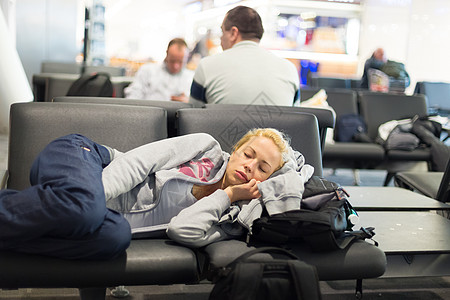 疲倦的女旅行者睡在机场大堂铁路飞机场旅游平台民众运输小憩休息移民图片