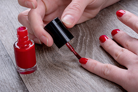 女性双手涂红指甲清漆温泉美容师手指治疗魅力刷子沙龙护理身体美甲背景图片