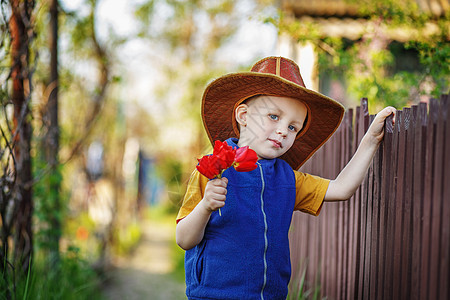 一个小男孩的肖像 站在一顶大帽子和一束花图片