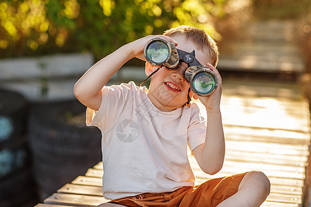 小男孩在河岸看望双筒望远镜芦苇支撑青年快乐微笑童年码头眼镜喜悦幸福图片