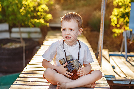小男孩在河岸通过迷彩望远镜看望着小男孩图片