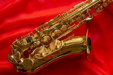 美丽的金色萨克斯风波浪状爵士乐萨克斯管音乐材料红色背景艺术光泽织物背景