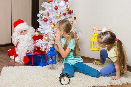 两个拿着手电筒的女孩去看圣诞老人 他试图小心翼翼地将礼物放在圣诞树下图片